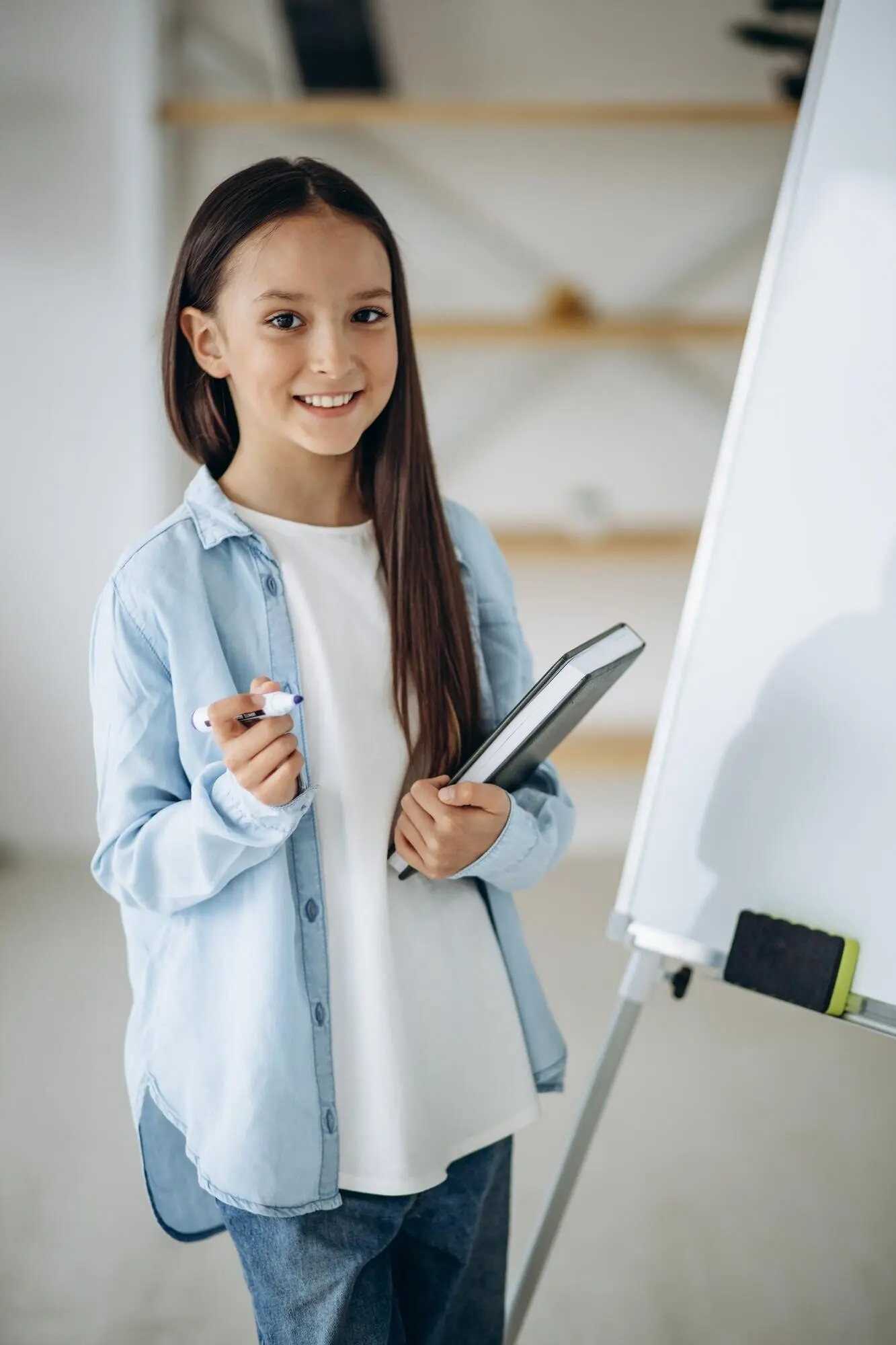 Маленькая девочка пишет на белой доске.