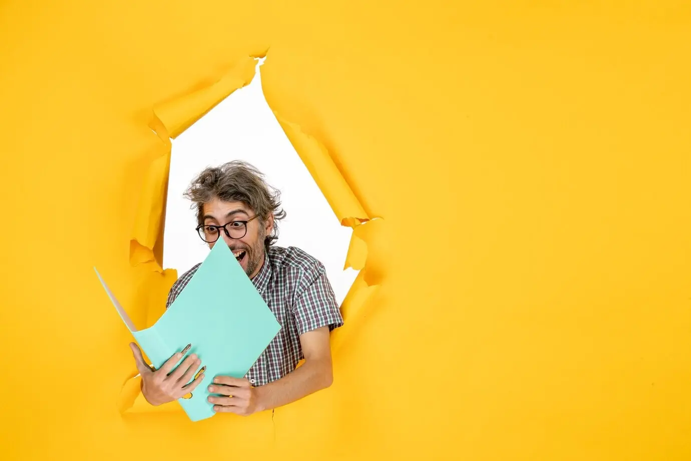 Фронтальный вид обычного мужчины с зелёной папкой на фоне жёлтой стены.